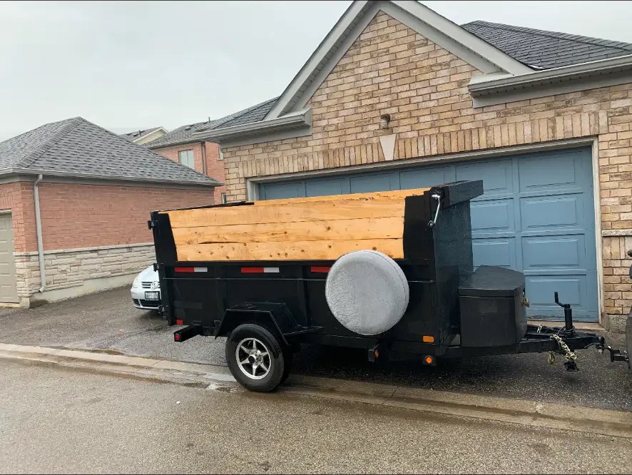 V Rentals 5x10 dump trailer parked in a residential driveway, side profile view